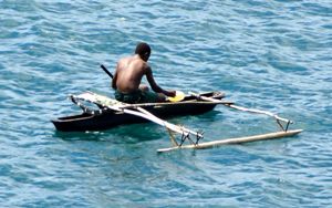 fisherman in a canoe in Papua, New Guinea, presenting on of the exotic luxury travel adventures